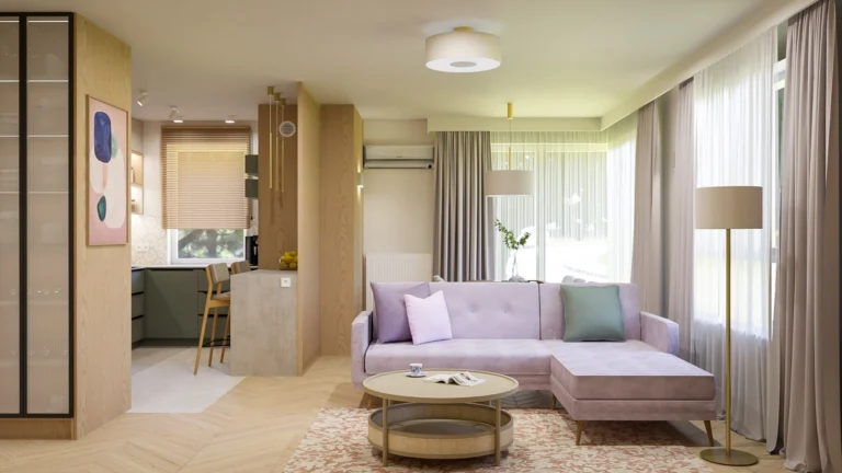 Salon z pastelową sofą narożną, lekkimi zasłonami i dużymi przeszkleniami, połączony z kuchnią i jadalnią; wnętrze utrzymane w jasnej, ciepłej kolorystyce.